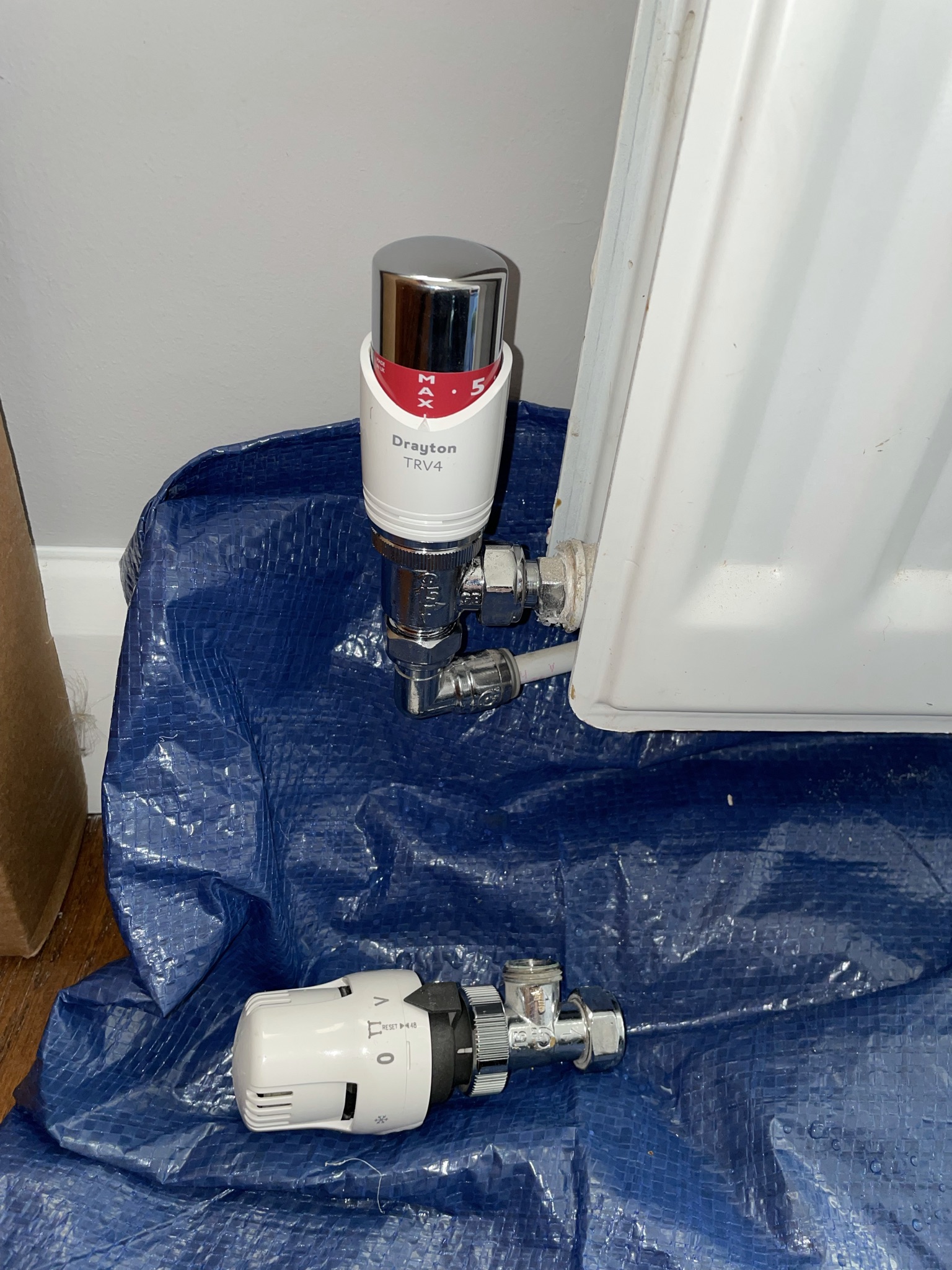Thermostatic radiator valves being fitted with a dust sheet down